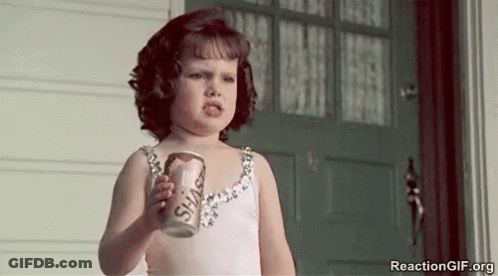 A Little Girl Is Holding A Can Of Soda And Making A Face . GIF