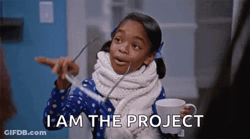 A Little Girl Is Holding A Cup Of Coffee And Pointing At Something While Saying I Am The Project . GIF