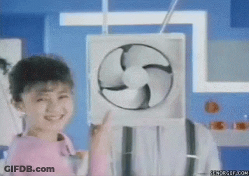 A Little Girl Is Holding A Fan In Front Of Her Face And Smiling . GIF