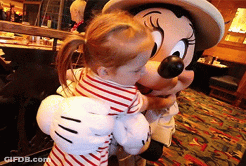 A Little Girl Is Hugging A Mickey Mouse Mascot GIF