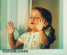 A Little Girl Is Looking Out Of A Window And Waving GIF