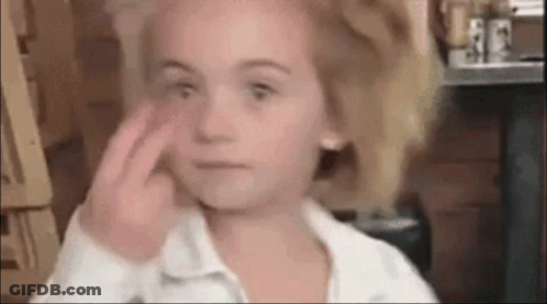 A Little Girl Is Making A Funny Face While Applying Makeup To Her Face . GIF