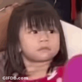 A Little Girl Is Making A Funny Face While Looking At A Cell Phone . GIF