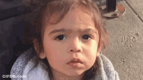 A Little Girl Is Making A Funny Face While Standing On The Sidewalk . GIF