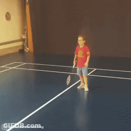 A Little Girl Is Playing Badminton On A Blue Court . GIF