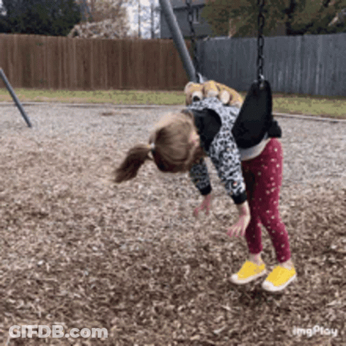 A Little Girl Is Playing On A Swing In A Park GIF
