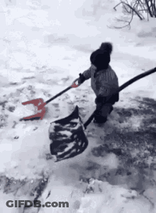 A Little Girl Is Shoveling Snow With A Shovel And A Bag . GIF