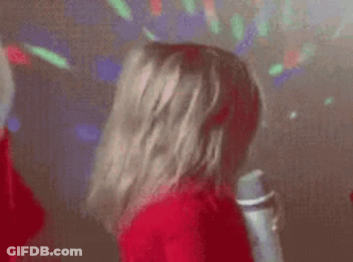 A Little Girl Is Singing Into A Microphone While Dancing . GIF