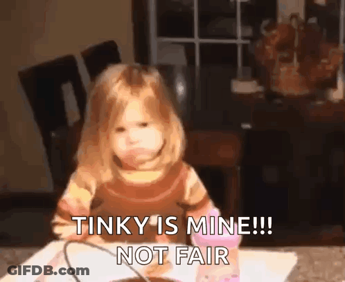 A Little Girl Is Sitting At A Table And Making A Funny Face And Saying That Tinky Is Mine !! Not Fair . GIF