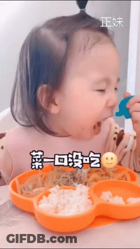 A Little Girl Is Sitting At A Table Eating Food From An Orange Plate With A Smiley Face On It . GIF