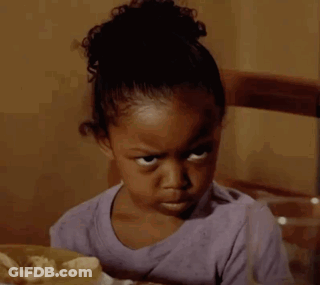 A Little Girl Is Sitting At A Table With A Bag Of Chips In Front Of Her GIF