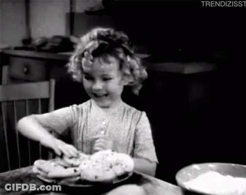 A Little Girl Is Sitting At A Table With A Bowl Of Flour And A Plate Of Food . GIF