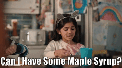 A Little Girl Is Sitting At A Table With A Cup Of Maple Syrup GIF