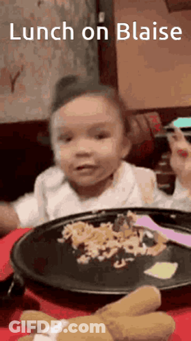 A Little Girl Is Sitting At A Table With A Plate Of Food And A Teddy Bear . GIF