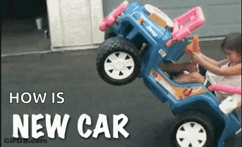 A Little Girl Is Sitting In A Blue Toy Car . GIF