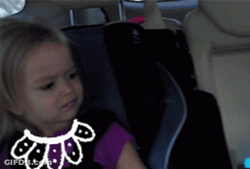 A Little Girl Is Sitting In A Car Seat With A Drawing Of A Cat On Her Shirt GIF