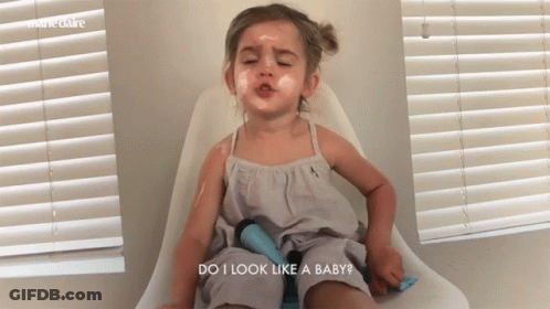 A Little Girl Is Sitting In A Chair With Her Eyes Closed And The Words Do I Look Like A Baby Above Her GIF