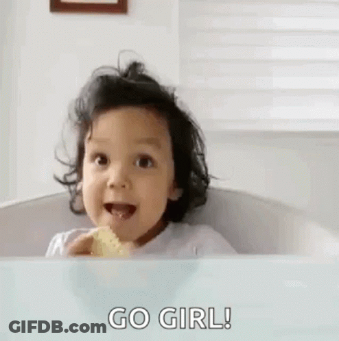 A Little Girl Is Sitting In A High Chair Eating A Piece Of Food And Giving The Middle Finger . GIF
