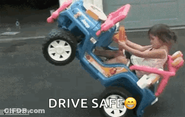 A Little Girl Is Sitting In A Toy Car With The Words Drive Safe Written On It . GIF