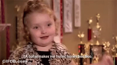 A Little Girl Is Sitting In Front Of A Christmas Tree And Talking About A Dollar Making Her Holler . GIF