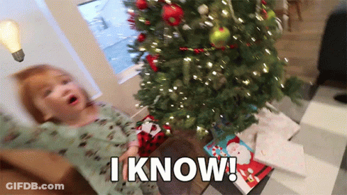A Little Girl Is Sitting In Front Of A Christmas Tree With The Words I Know Above Her GIF
