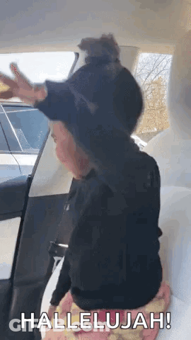 A Little Girl Is Sitting In The Back Seat Of A Tesla Model 3 And Making A Funny Face . GIF