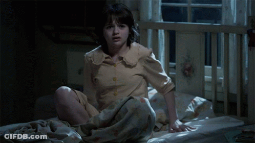 A Little Girl Is Sitting On A Bed With A Blanket Over Her Head GIF