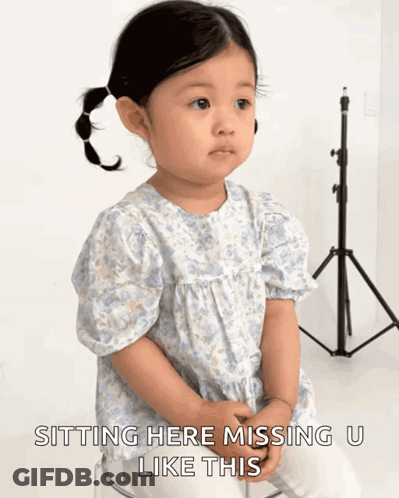 A Little Girl Is Sitting On A Clear Stool With The Words " Sitting Here Missing U Like This " Below Her GIF
