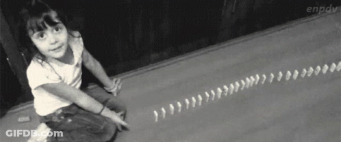 A Little Girl Is Sitting On The Floor Playing With Dominoes GIF