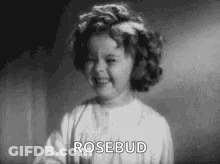 A Little Girl Is Smiling In A Black And White Photo And Says `` Rosebud '' . GIF