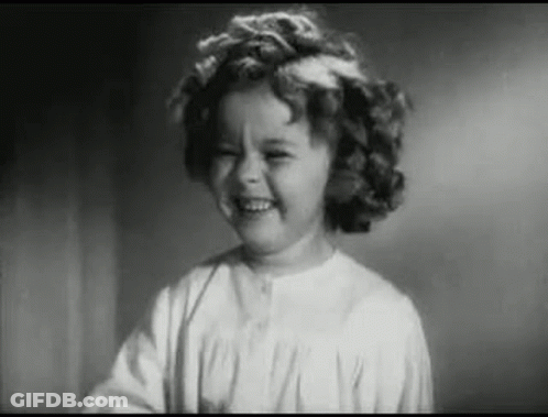 A Little Girl Is Smiling In A Black And White Photo . GIF