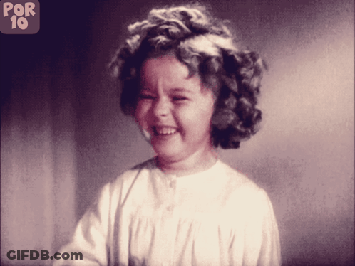 A Little Girl Is Smiling In Front Of A Sign That Says Por 10 On It GIF