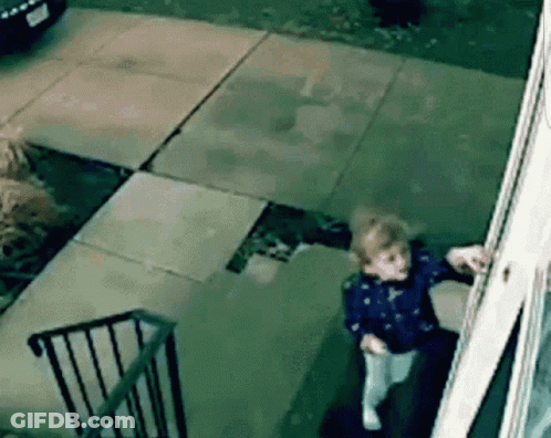 A Little Girl Is Standing In Front Of A House Looking Out A Window . GIF