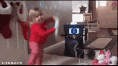 A Little Girl Is Standing In Front Of A Karaoke Machine With The Letter E On It GIF