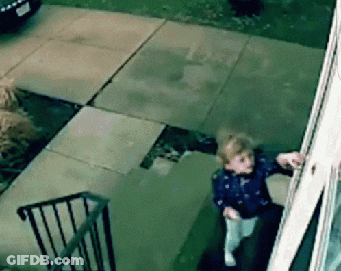 A Little Girl Is Standing On The Steps Of A Building Looking Out A Window GIF