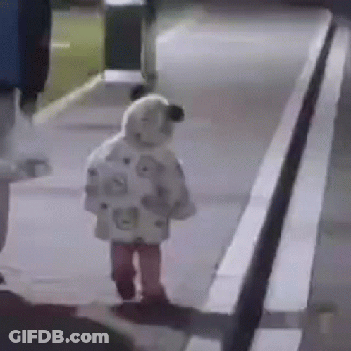 A Little Girl Is Walking Down A Sidewalk At Night Wearing A Sheep Costume . GIF