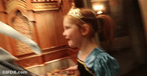 A Little Girl Is Wearing A Tiara And A Blue Dress While Standing Next To A Man . GIF
