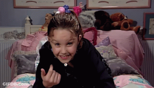 A Little Girl Laying On A Bed With Stuffed Animals On It GIF