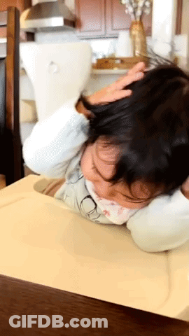 A Little Girl Laying On A Table With Her Head Resting On A Pillow GIF