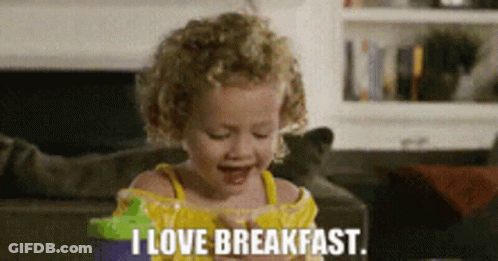 A Little Girl Says I Love Breakfast While Eating A Snack GIF