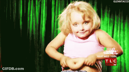 A Little Girl Shows Off Her Stomach In Front Of A Green Curtain That Says Tlc On It GIF