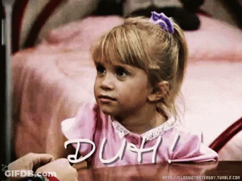 A Little Girl Sitting At A Table With The Word Duh Written On The Table GIF