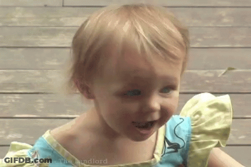 A Little Girl Wearing A Blue And Yellow Dress Is Smiling . GIF