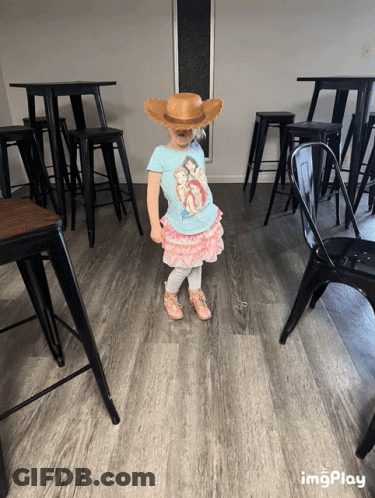 A Little Girl Wearing A Cowboy Hat And A Disney Shirt GIF
