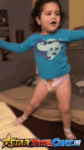 A Little Girl Wearing A Diaper And A Blue Shirt With A Heart On It Is Jumping In The Air GIF