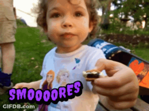 A Little Girl Wearing A Frozen Shirt Is Holding A Smores In Her Hand GIF