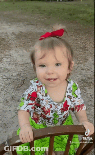 A Little Girl Wearing A Green And White Dress Is Sitting On A Chair With A Tiktok Watermark GIF