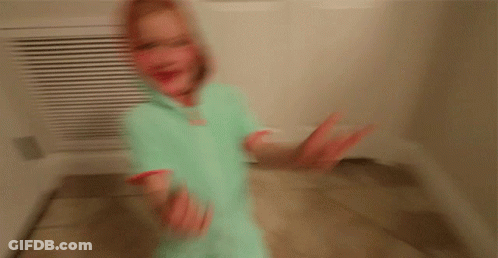 A Little Girl Wearing A Hoodie Is Standing In A Hallway GIF