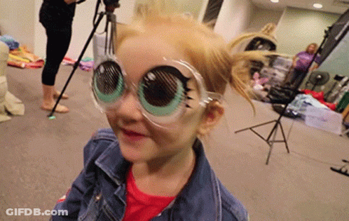 A Little Girl Wearing A Pair Of Glasses That Look Like Big Eyes . GIF