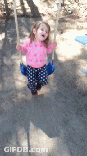 A Little Girl Wearing A Pink Shirt And Blue Polka Dot Pants Is Swinging On A Blue Swing GIF